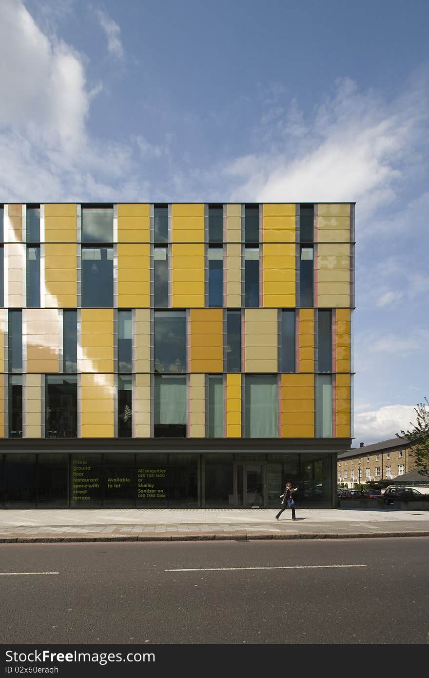 Modern office building with coloured facade panels and person walking by. Modern office building with coloured facade panels and person walking by