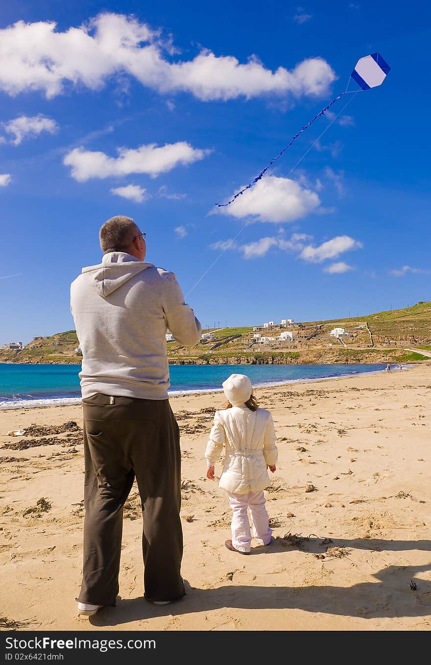 A little girl and dad run a kite in the sky with clouds on the beach near the sea. A little girl and dad run a kite in the sky with clouds on the beach near the sea