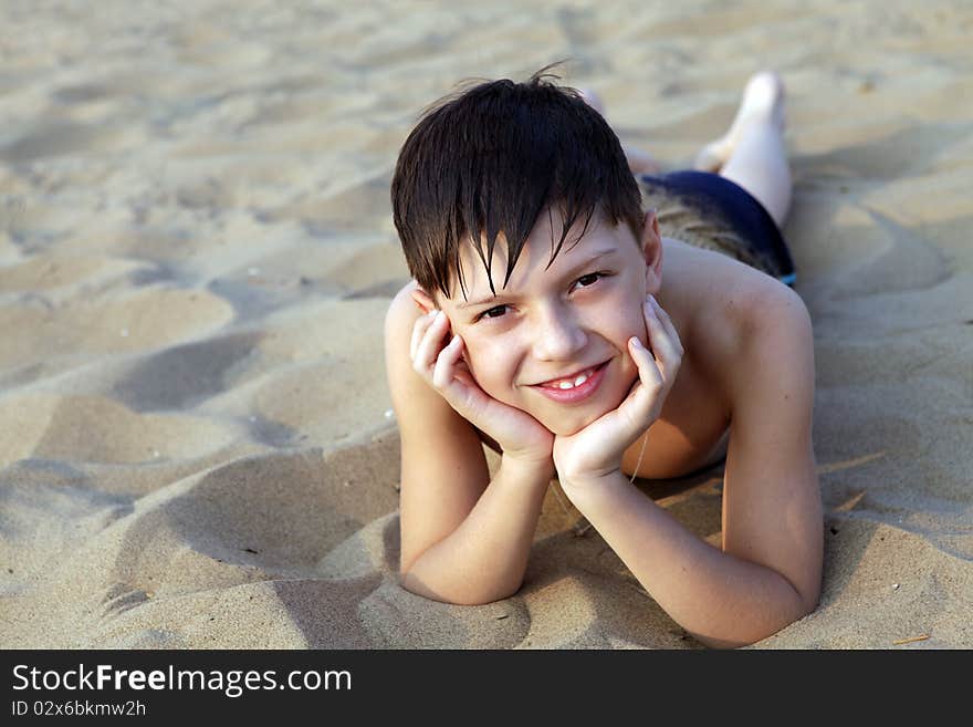 Smiling boy sunbathes on a beach