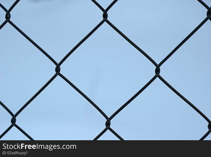 Metal fence with blue sky on the background.