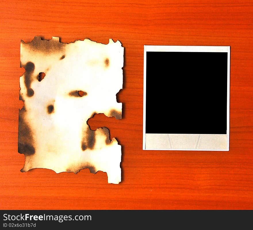 Old photos and burnt paper on a wooden background