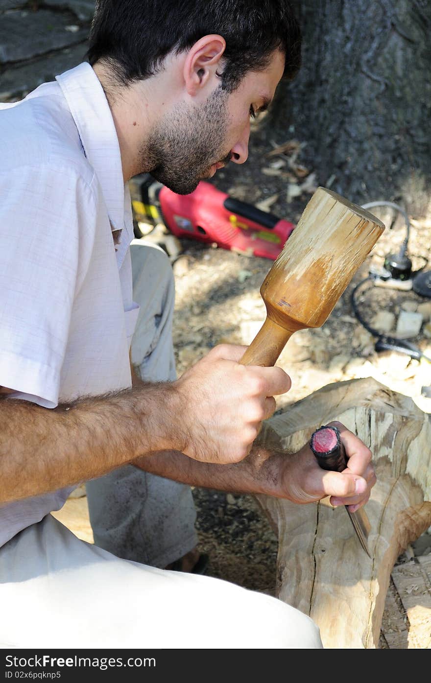 Young man sculpting wood material. Young man sculpting wood material