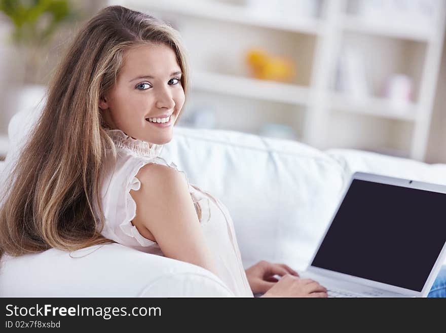 A beautiful young girl with a laptop at home. A beautiful young girl with a laptop at home