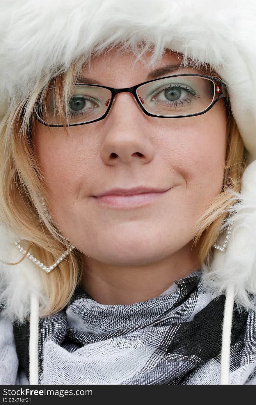 Cheeky portrait of a friendly smiling young woman with a white fur hat. Looking into the camera. Vertical Image. Cheeky portrait of a friendly smiling young woman with a white fur hat. Looking into the camera. Vertical Image.