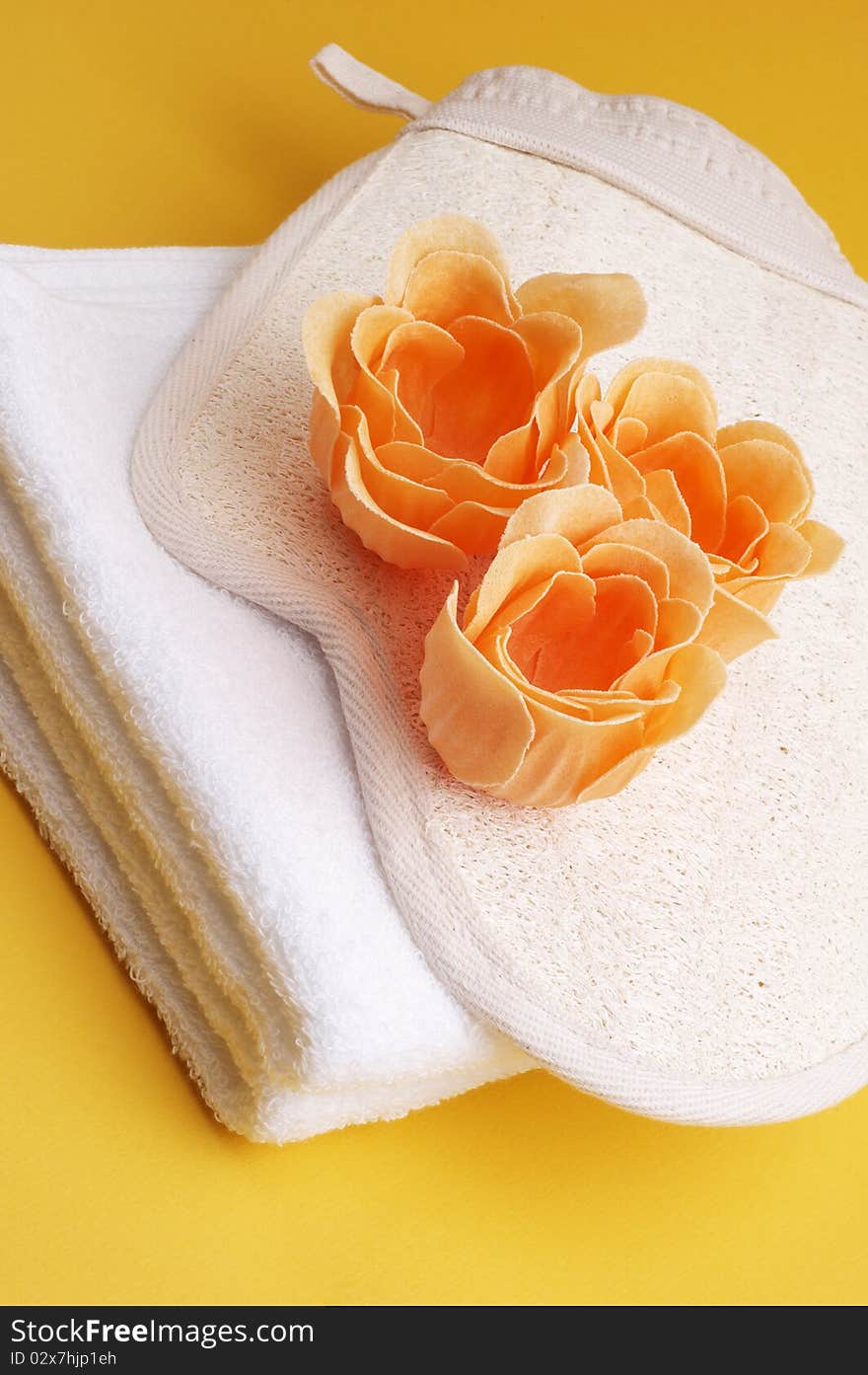 White towel with scented bath flowers and glove