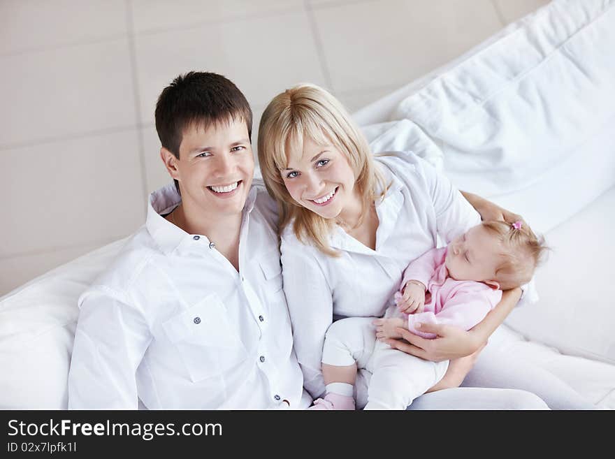 Happy young family with baby on the couch at home. Happy young family with baby on the couch at home