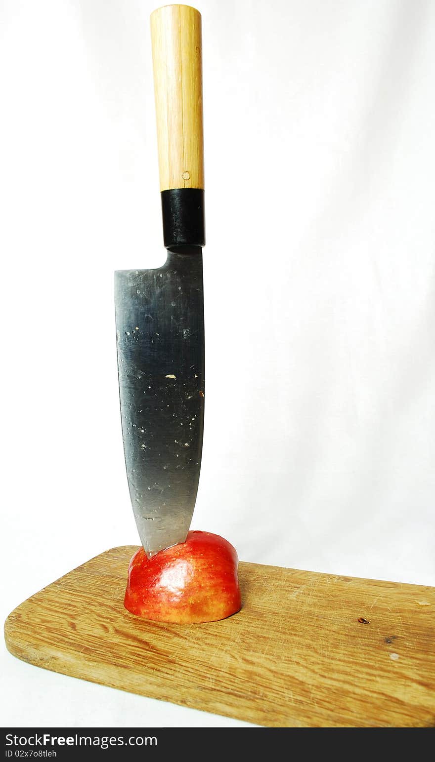 Half an apple in it plunged the knife, white background, still life, red juicy fruits of apple, colors of nature, food, juice, fruit, knife, cutting, cutting fruit, cutting board