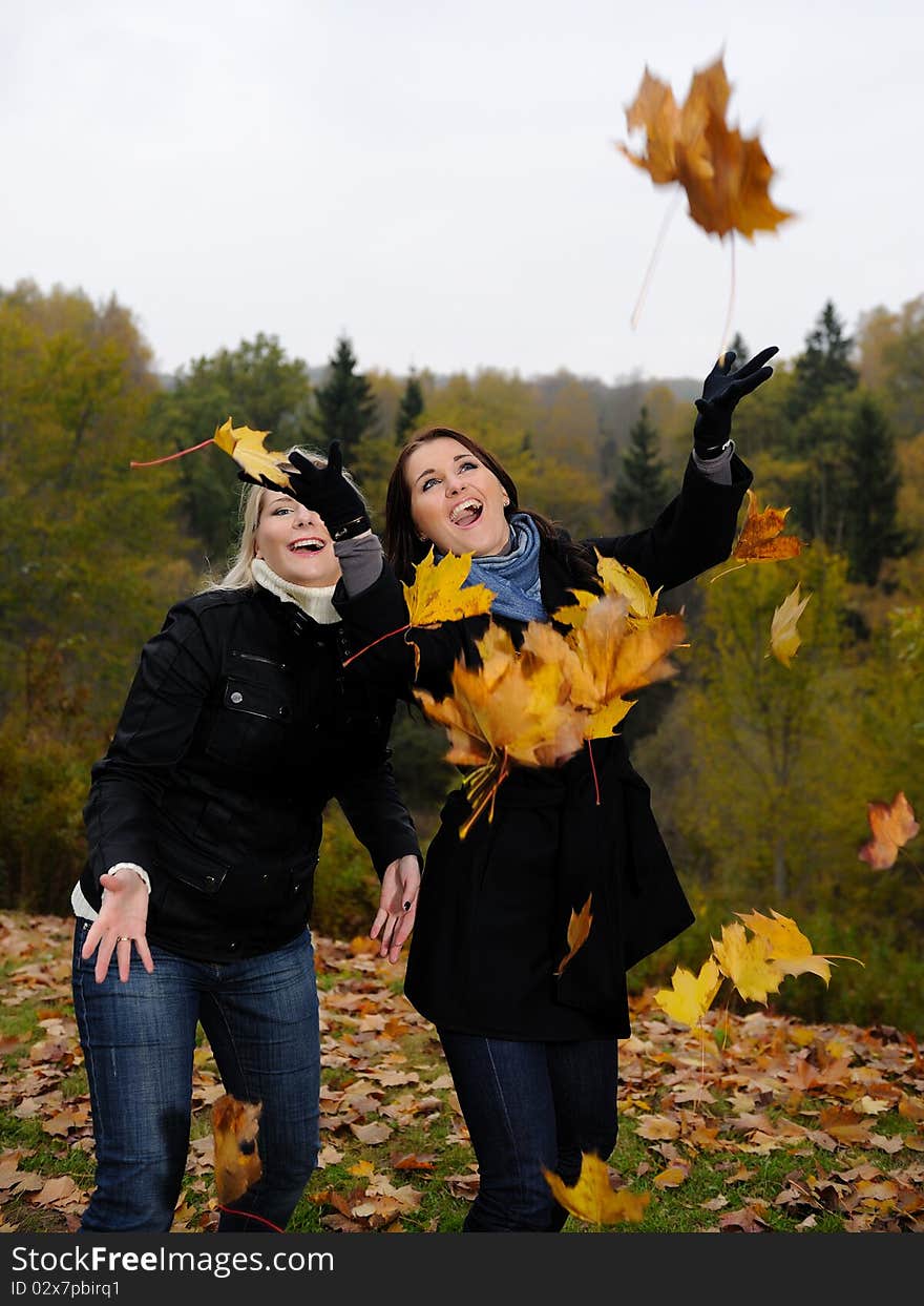 Two beautiful girl friends with autumn leafs