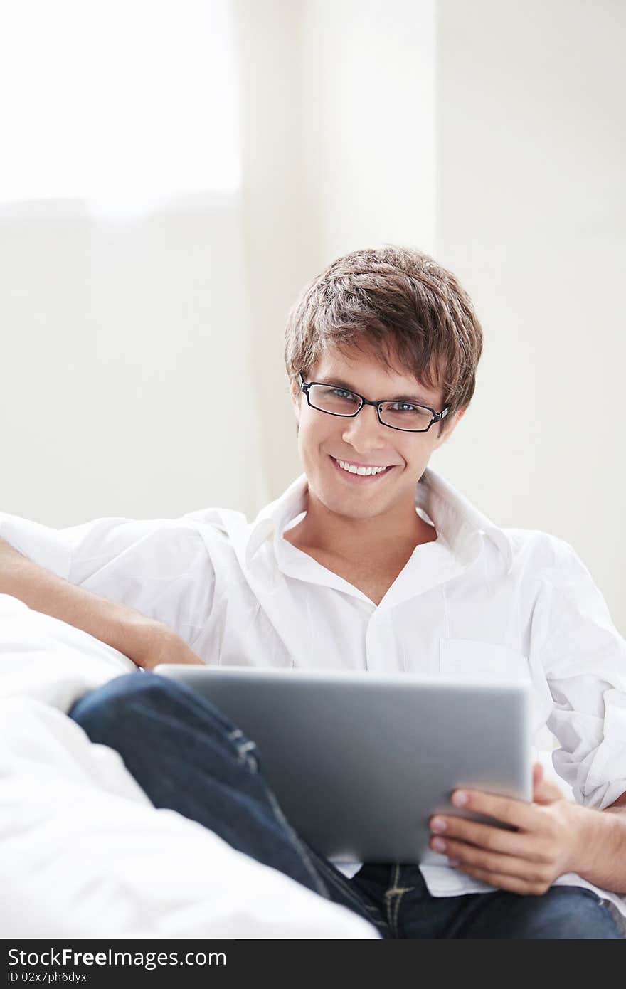 Young attractive man with laptop on sofa