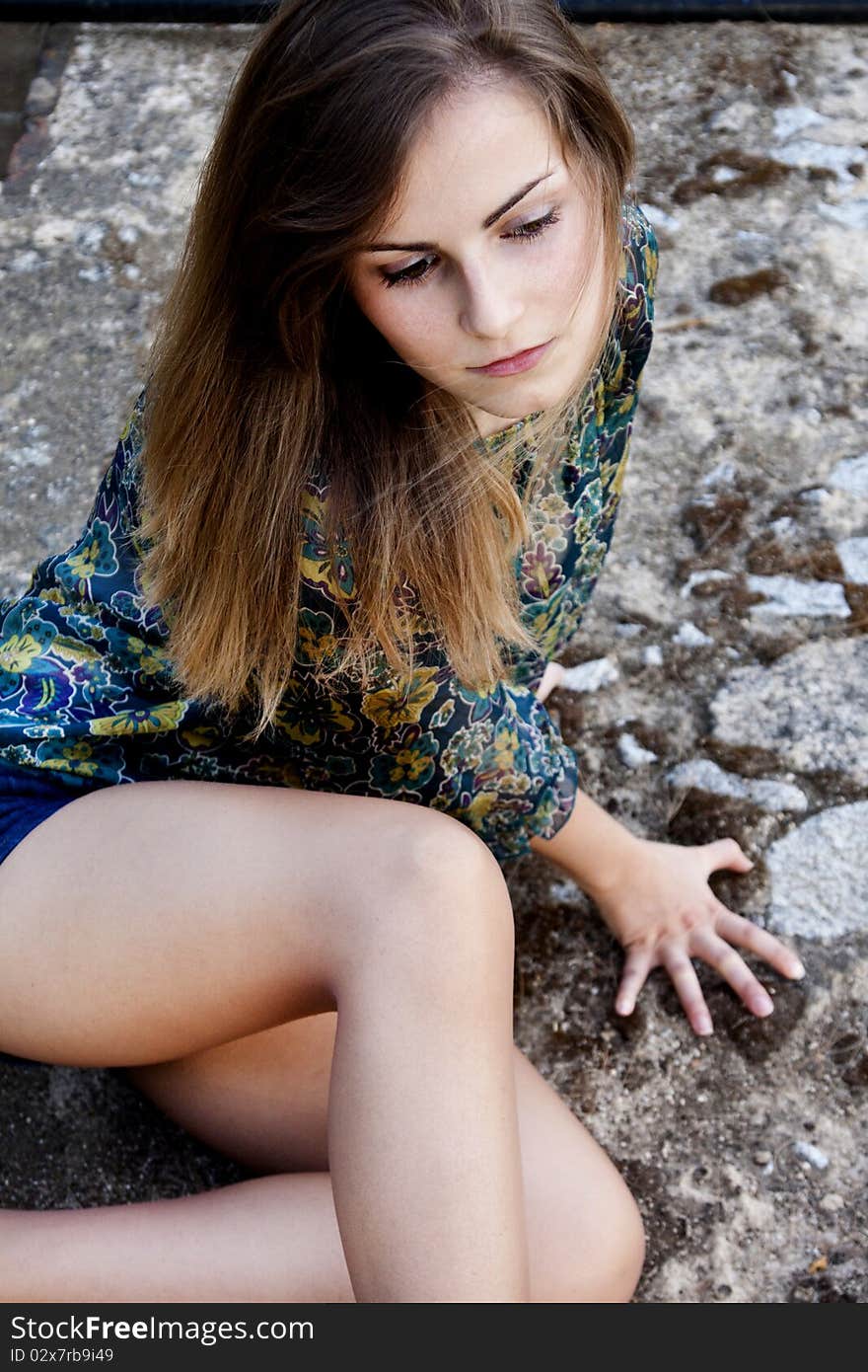 View of a beautiful girl on a floral blouse on top of a stone table. View of a beautiful girl on a floral blouse on top of a stone table.