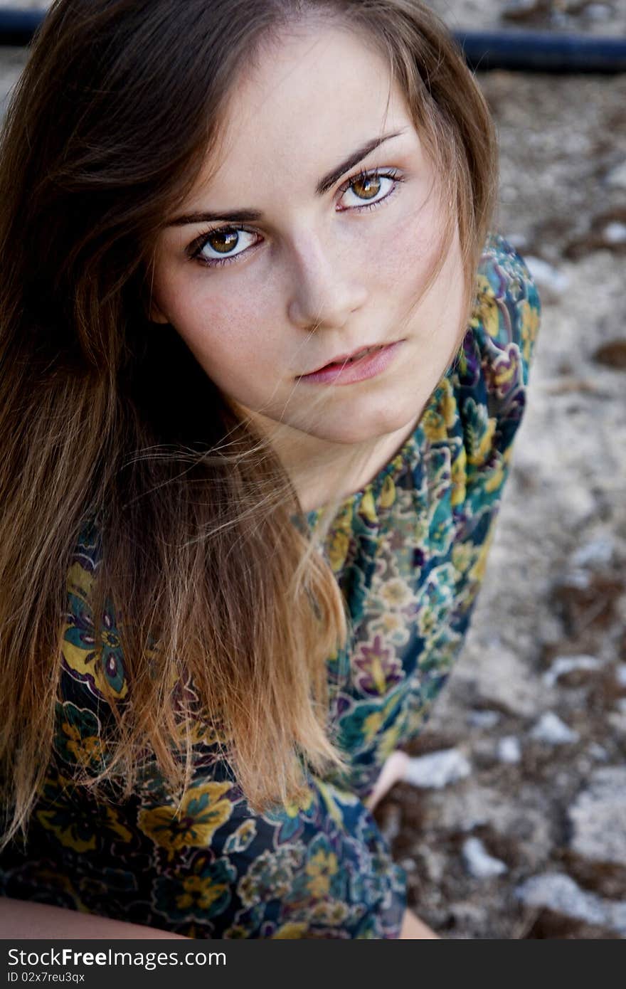 View of a beautiful girl on a floral blouse on a park. View of a beautiful girl on a floral blouse on a park.