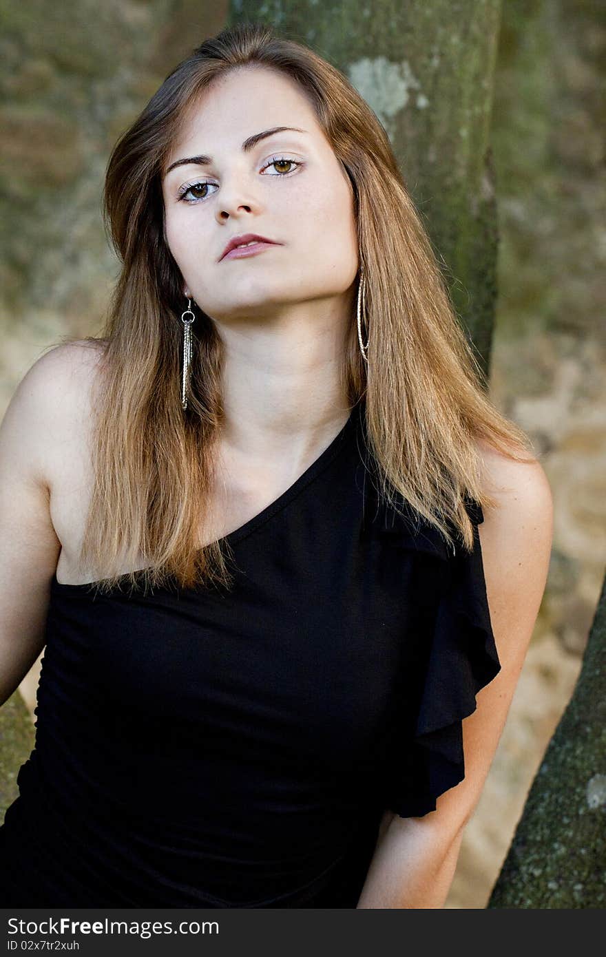 View of a beautiful girl on a black dress on a park. View of a beautiful girl on a black dress on a park.