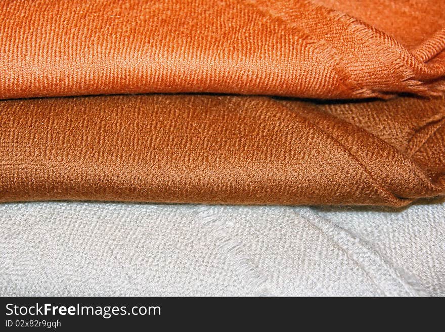 Brown and white folded pasmina shawls close-up. Brown and white folded pasmina shawls close-up.