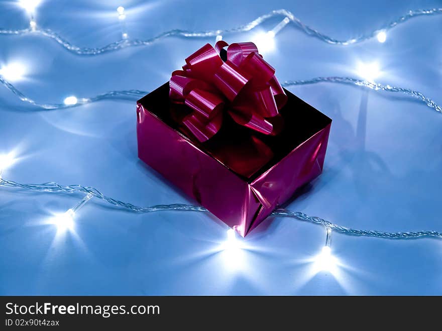 Red gift box with bow on white garland. Studio shot