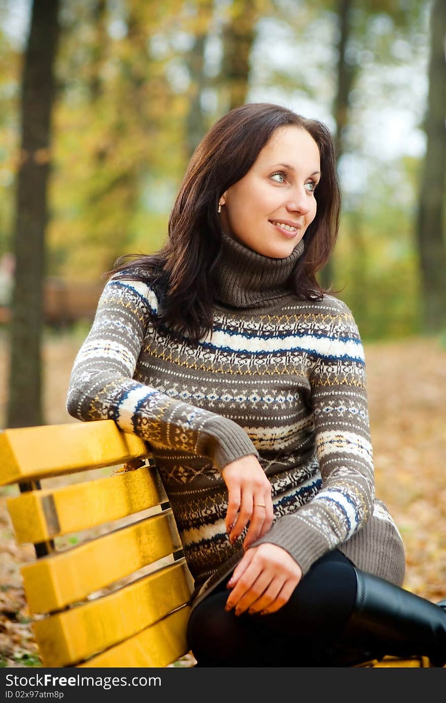 Young Woman Sitting On A Bench In Autumn Park