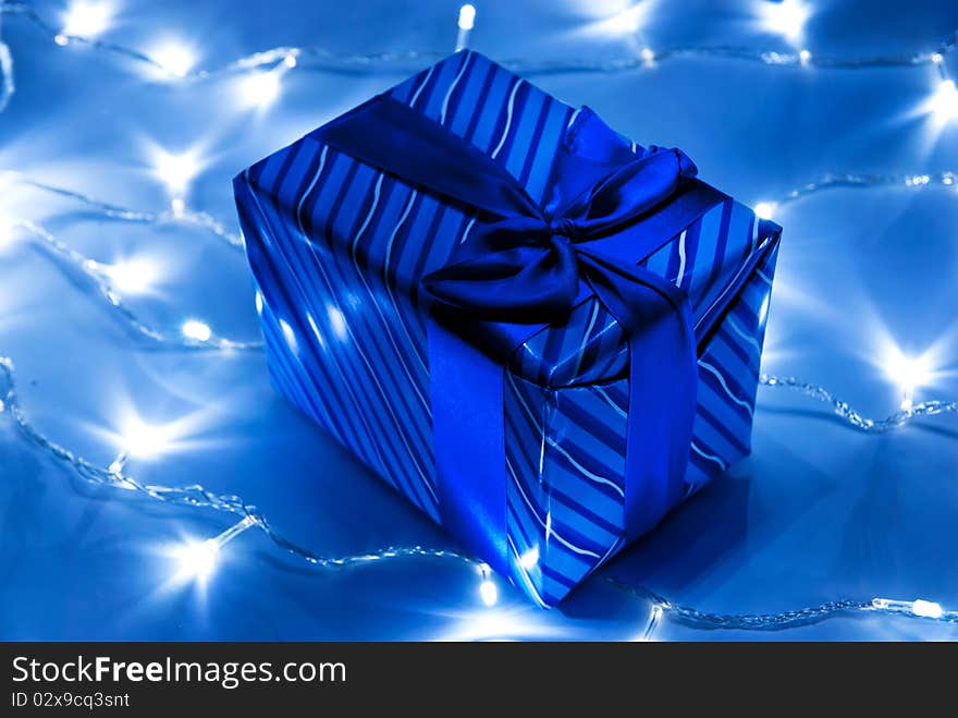 Blue gift box with garland background. Studio shot. Blue gift box with garland background. Studio shot