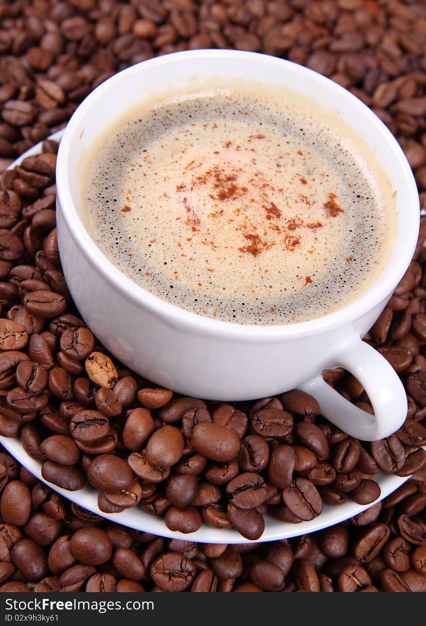 Cup of coffee surrounded by coffee beans