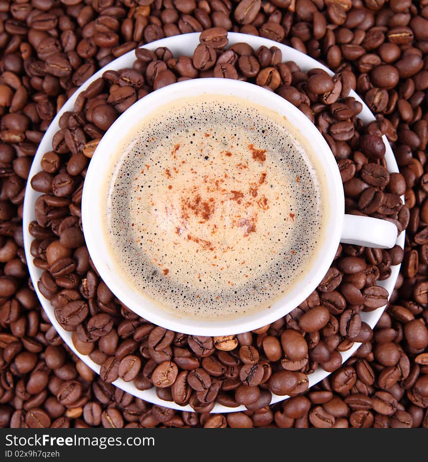 Cup of coffee surrounded by coffee beans