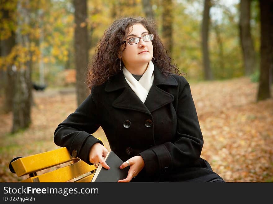 Prettty woman sitting with book on bench and dream. Prettty woman sitting with book on bench and dream