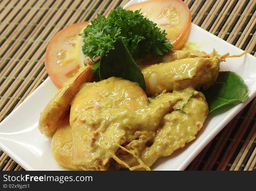 A dish of prawn in fermented durian sauce with sliced tomato and garnishing