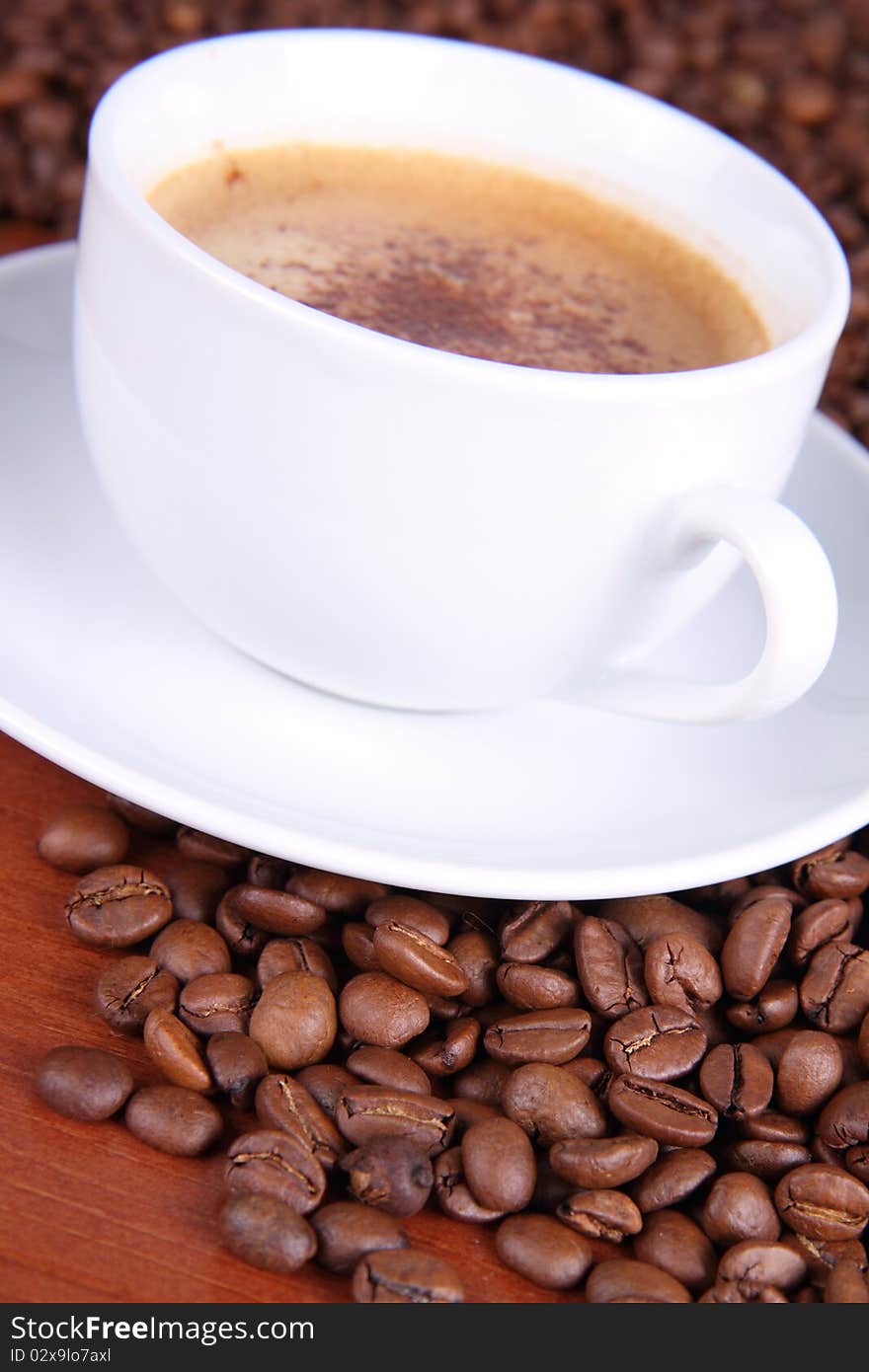 Cup of coffee with sprinkled with cinnamon with coffee beans around it on wooden background