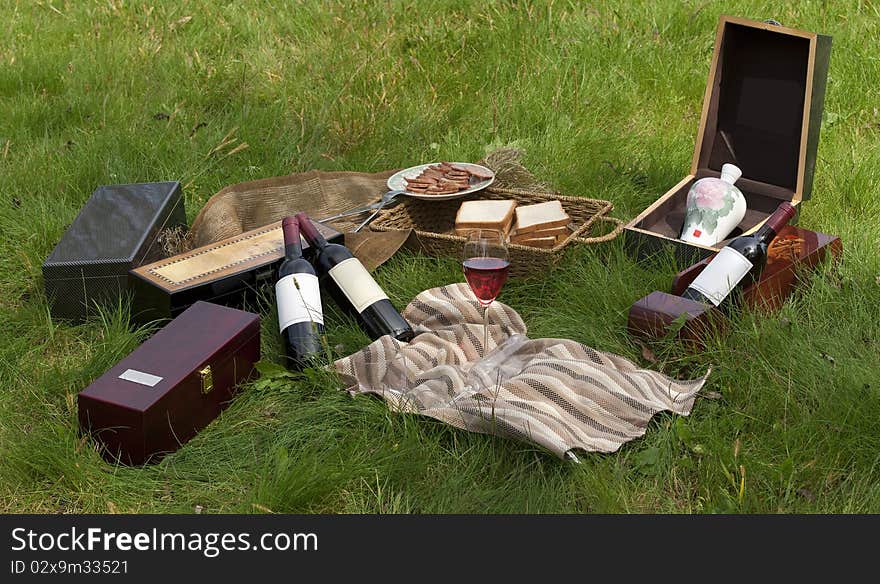 Picnic scene: wine bottles, glass, bread, wine boxes, still life