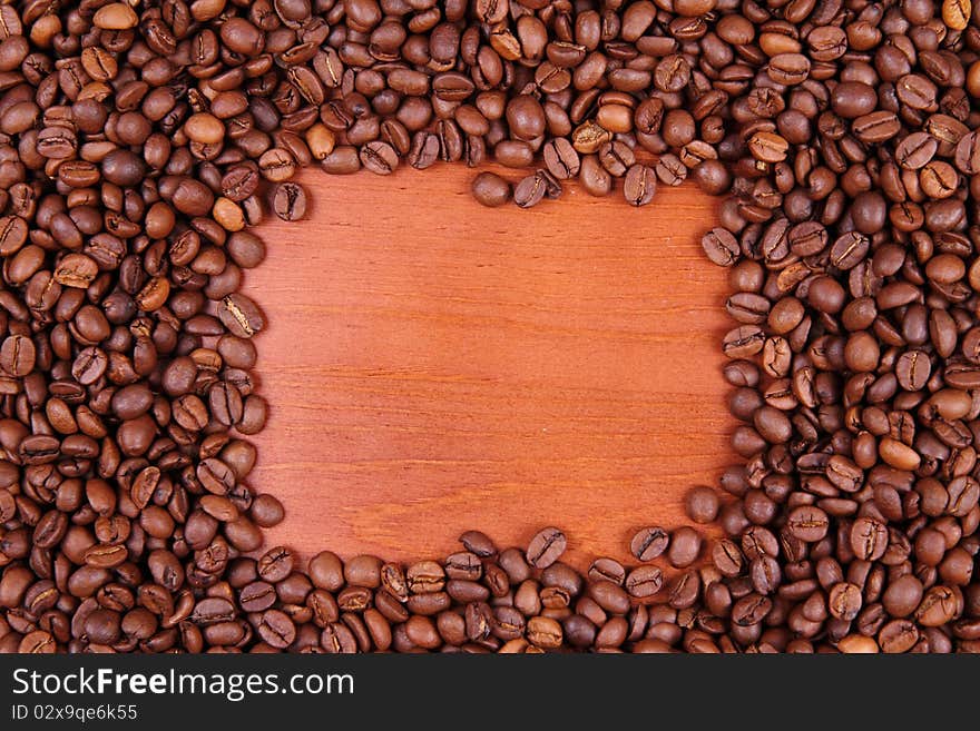 Coffee beans with wooden background in the middle with space for text. Coffee beans with wooden background in the middle with space for text