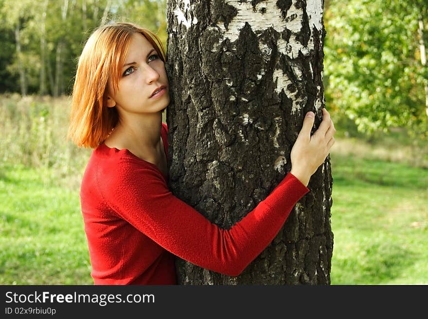 Beauty girl in red dress hug a tree, half body, looking at side. Beauty girl in red dress hug a tree, half body, looking at side