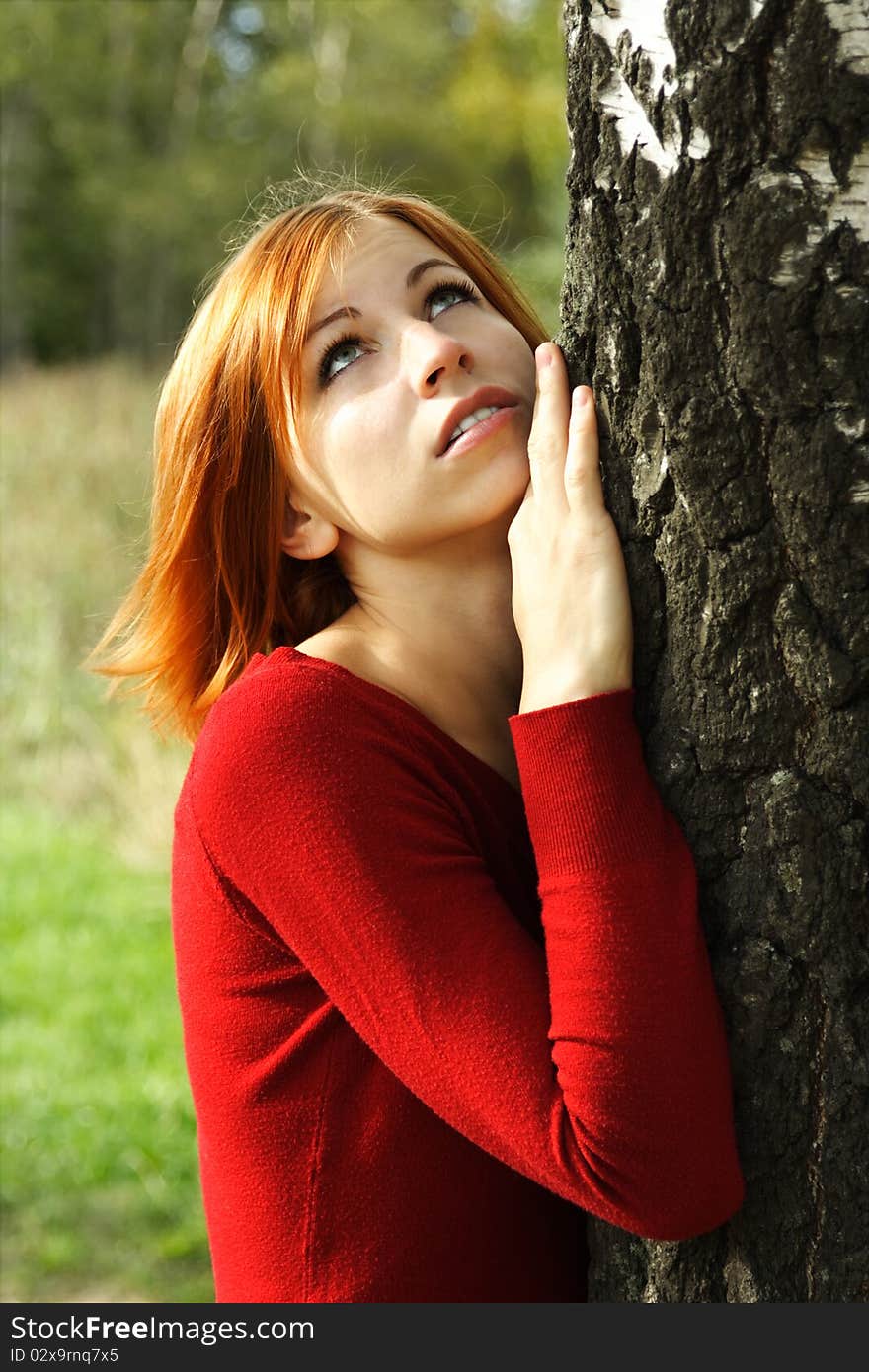 Beauty girl in red dress snuggle up to tree, half body, looking up