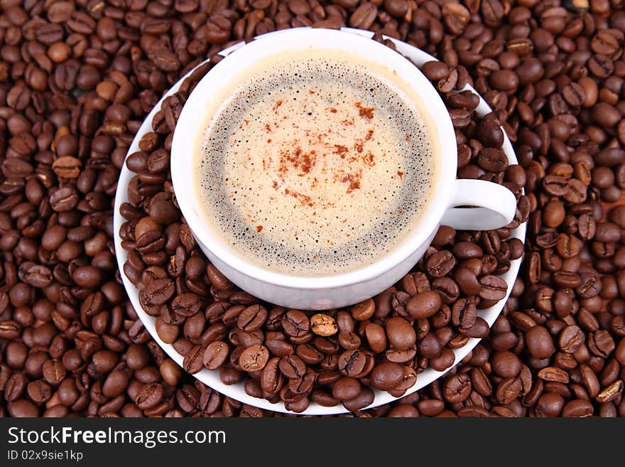 Cup of coffee with sprinkled with cinnamon with coffee beans around it