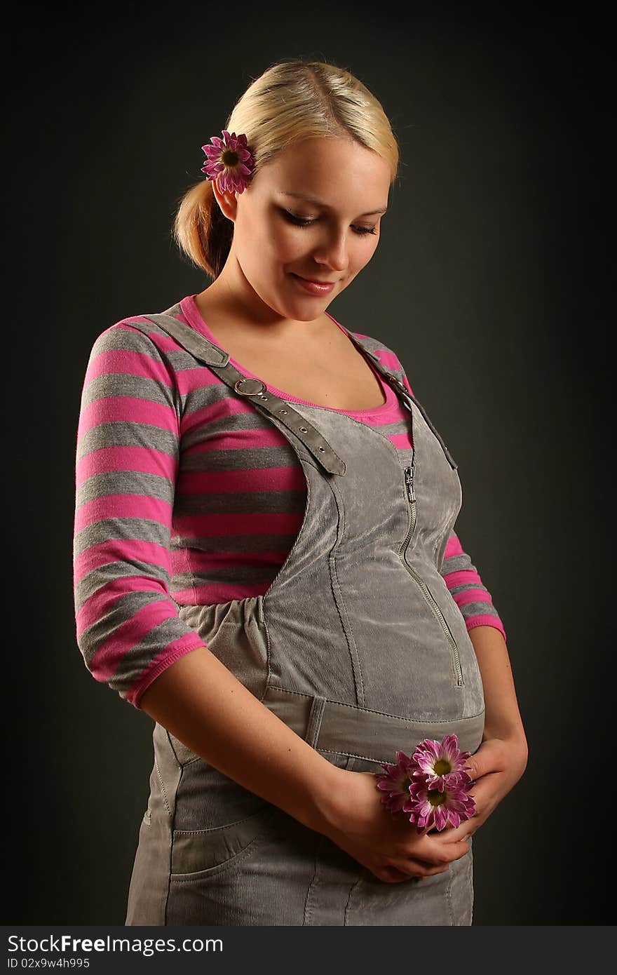 Pregnant young woman on dark background