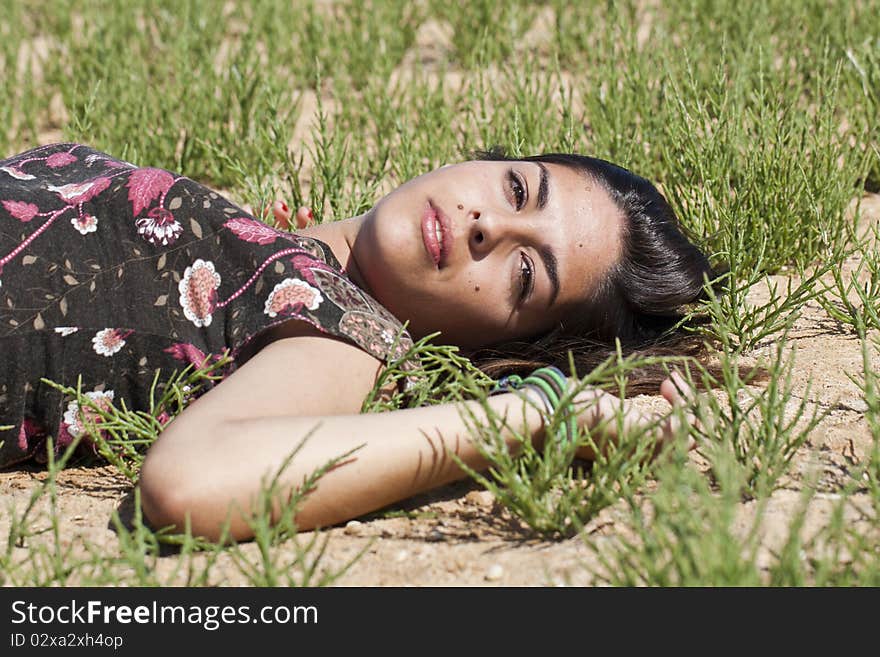 Beautiful girl with floral dress on the ground in a sunny day. Beautiful girl with floral dress on the ground in a sunny day.