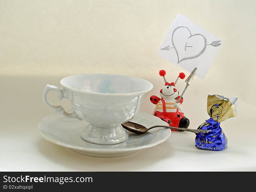 White coffee cup, candy and note with heart