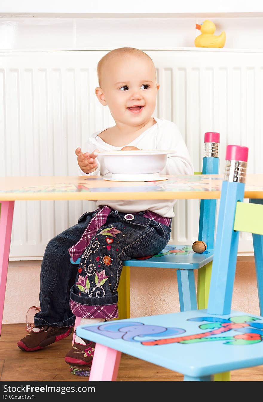 Beautiful baby girl sitting at the table