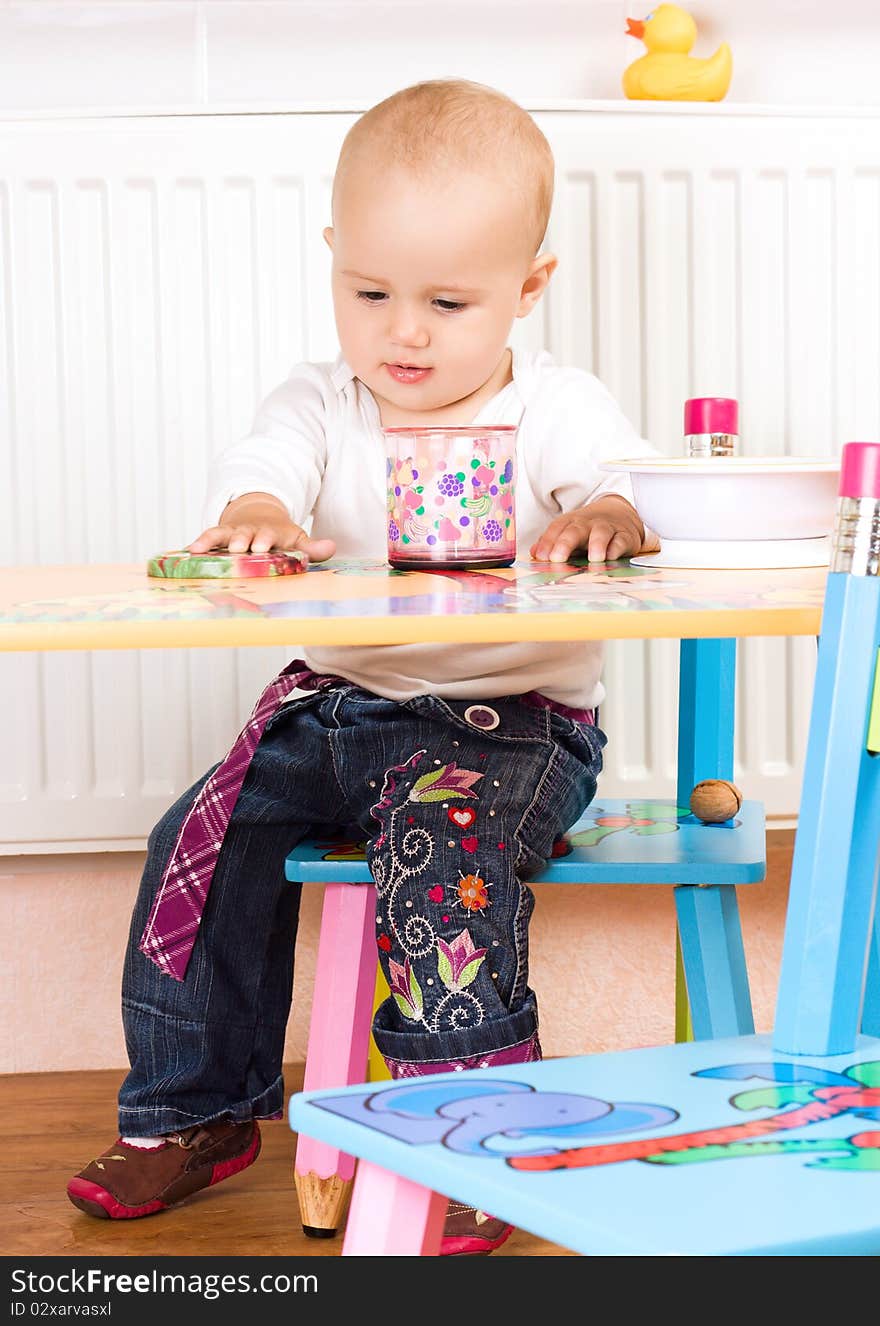 Beautiful baby girl sitting at the table