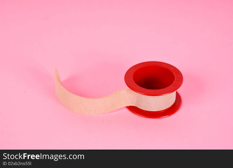 Roll of medical sticking plaster isolated on pink