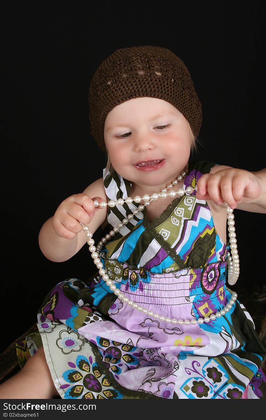 Beautiful toddler playing with a string of pearls. Beautiful toddler playing with a string of pearls