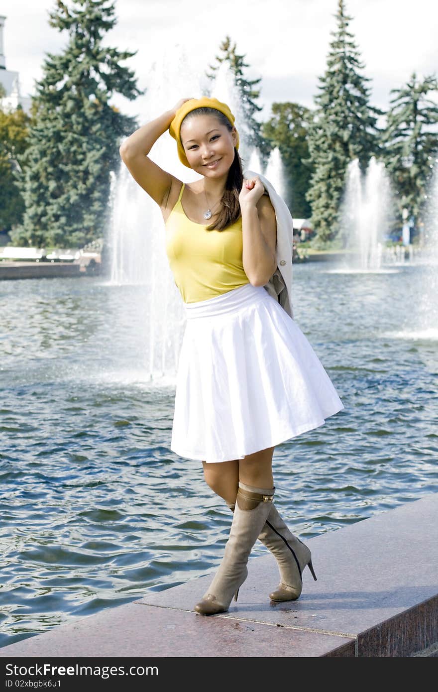 Happy girl walking near fountain in city