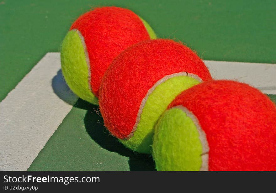 Yellow-red balls on a green tennis court. Yellow-red balls on a green tennis court