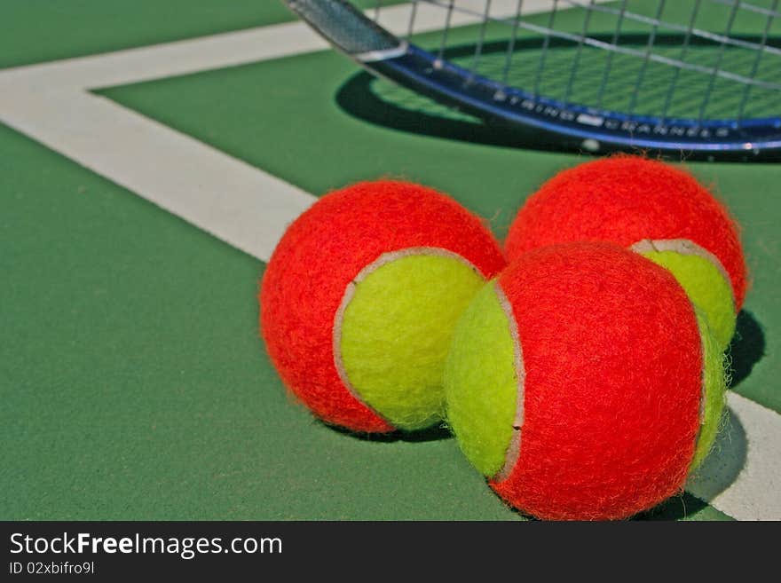 Yellow-red balls on a green tennis court. Yellow-red balls on a green tennis court