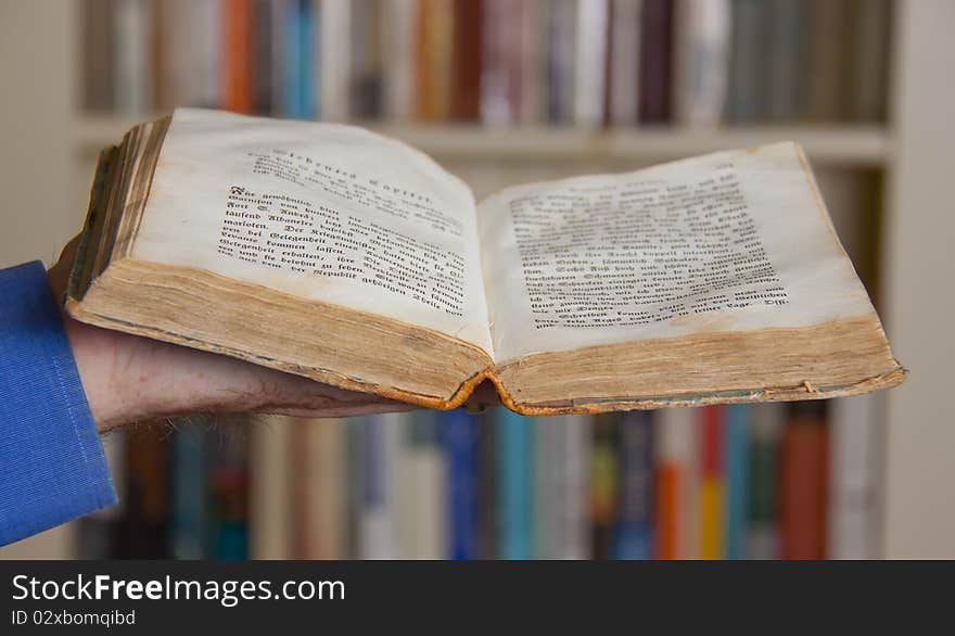 An old German book laid open, bookshelf in the background