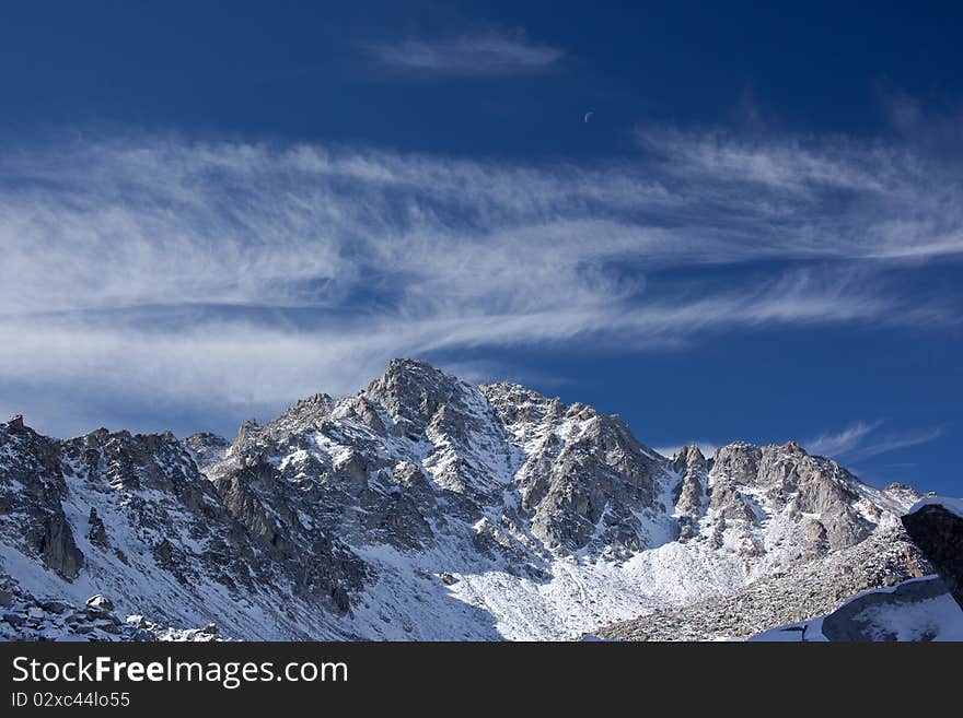 Photo of Pogranichny peak in Sayan Mountains. Moon is visible. Photo of Pogranichny peak in Sayan Mountains. Moon is visible.