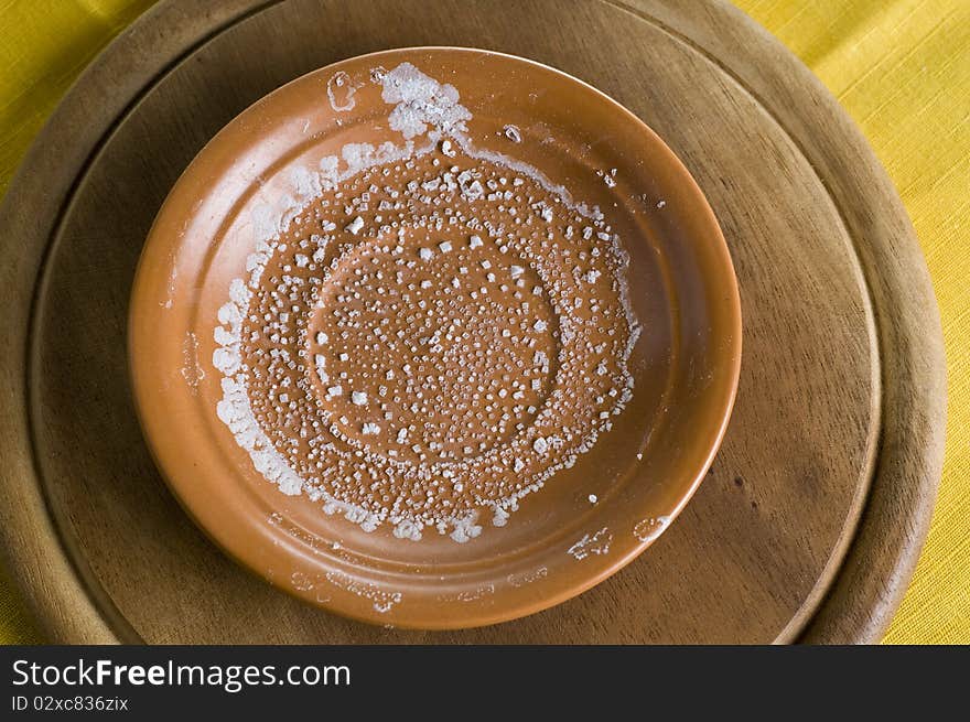 Salt crystallized over plate on wooden board. Salt crystallized over plate on wooden board