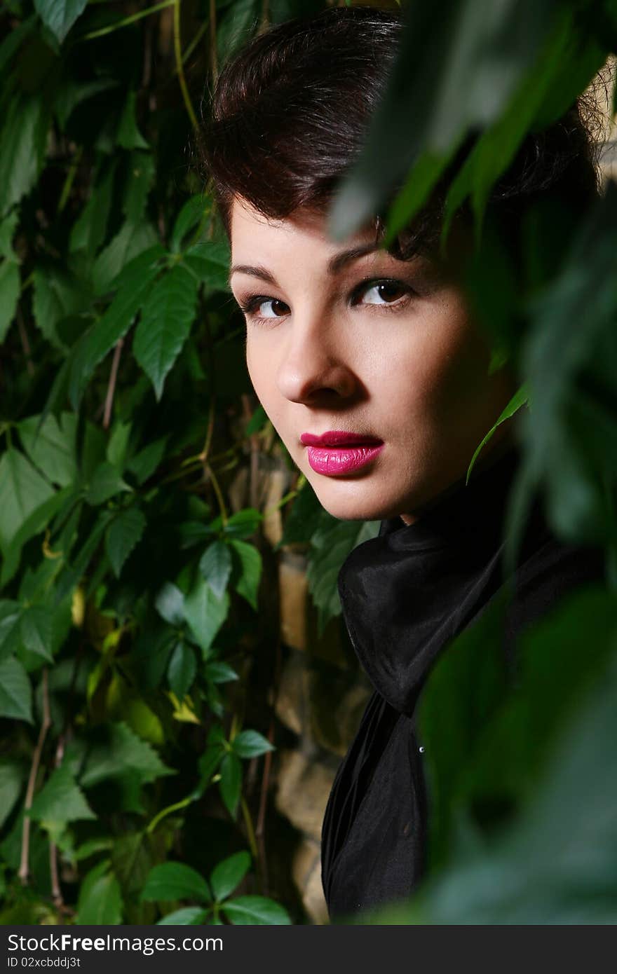 Young and attractive lady beside with brick wall, overgrown of vine leaves. Young and attractive lady beside with brick wall, overgrown of vine leaves