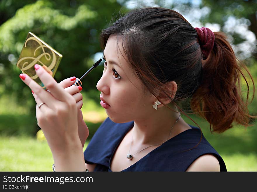 Young woman applying mascara using lash brush