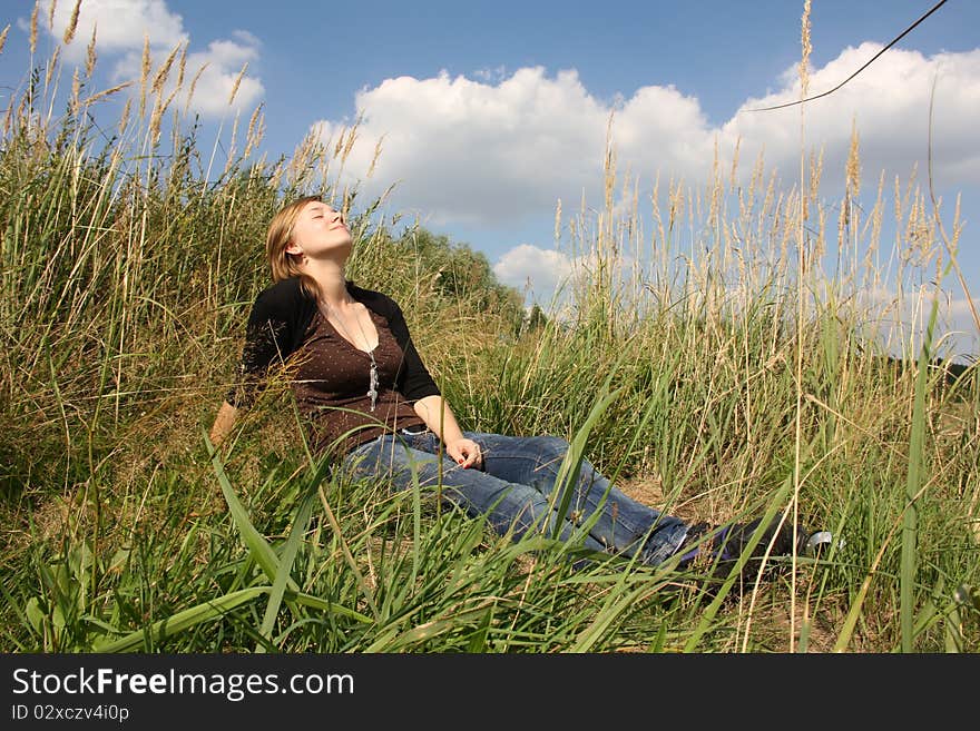 Young woman is sitting in the grass