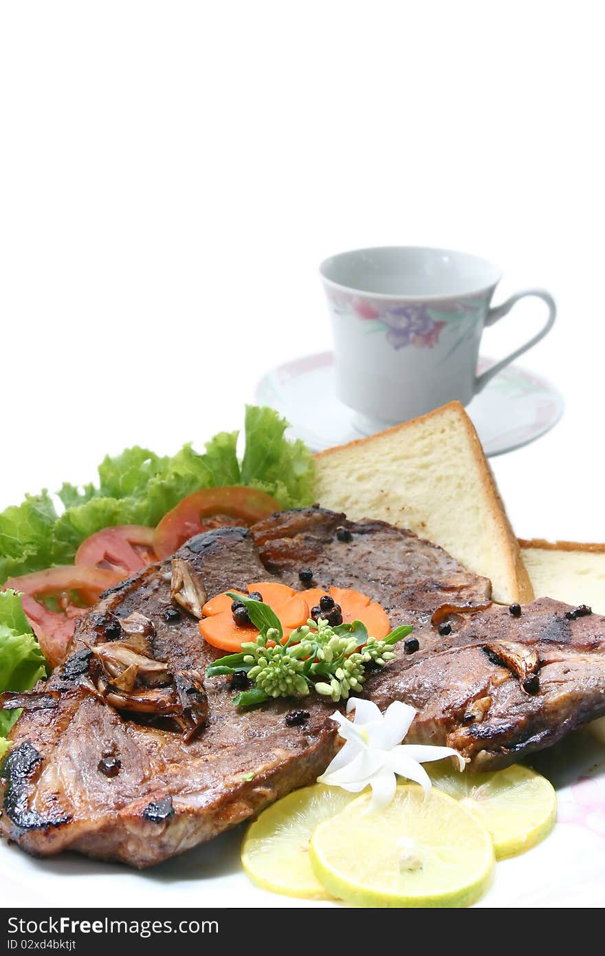 Closeup of T Bone Pepper Steak dressing by vegetable and bread with Coffee cup