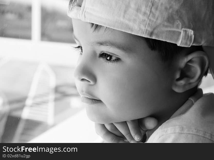 Portrait of little pretty thoughtful boy looking out of the window