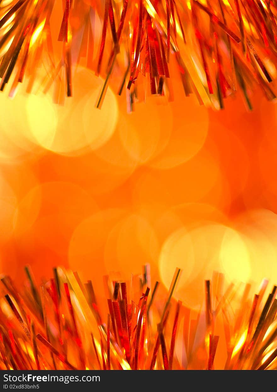 Orange christmas tinsel over blurred background. Orange christmas tinsel over blurred background