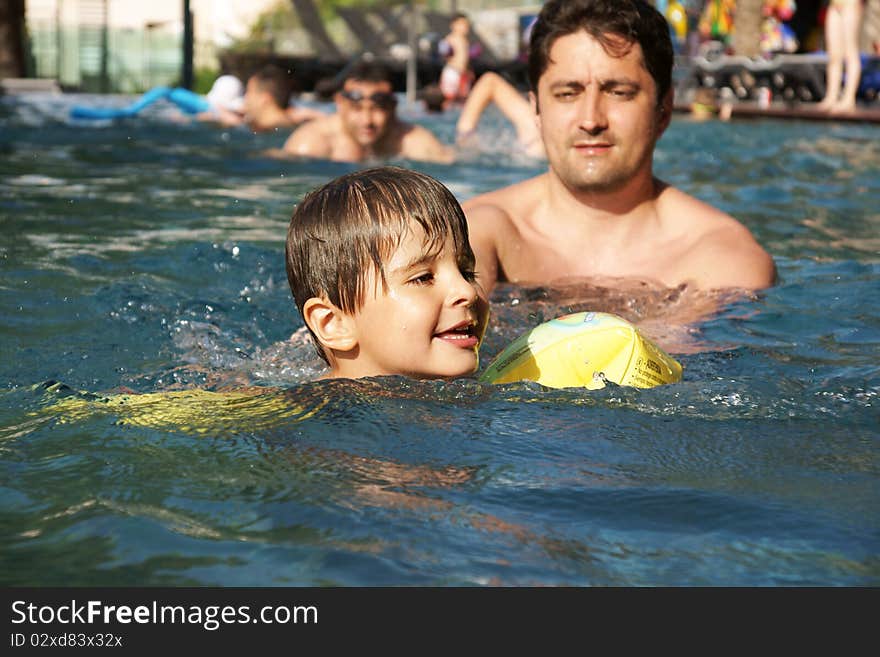 Youbg father teaching little joyful boy to swim, outdoot shot. Youbg father teaching little joyful boy to swim, outdoot shot